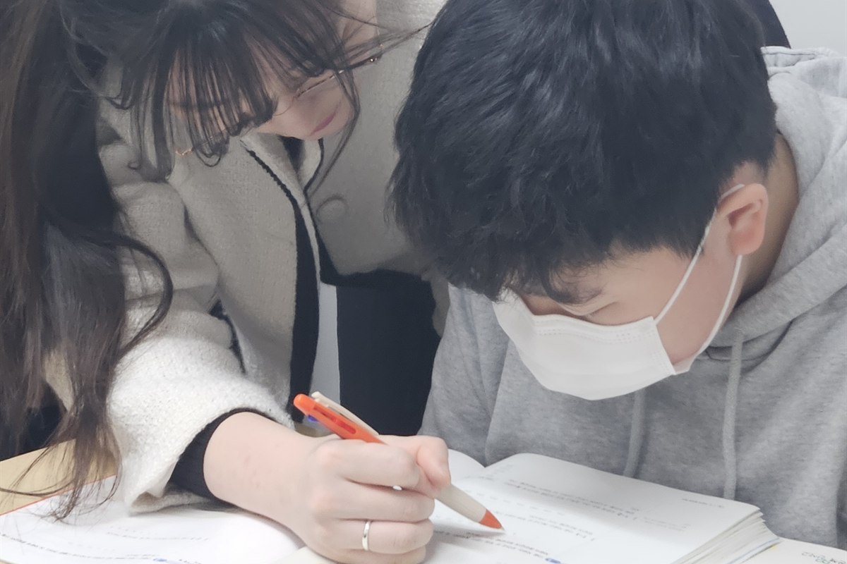 민주쌤이 초등학생 옆에서 문제를 짚어가며 지도하는 모습