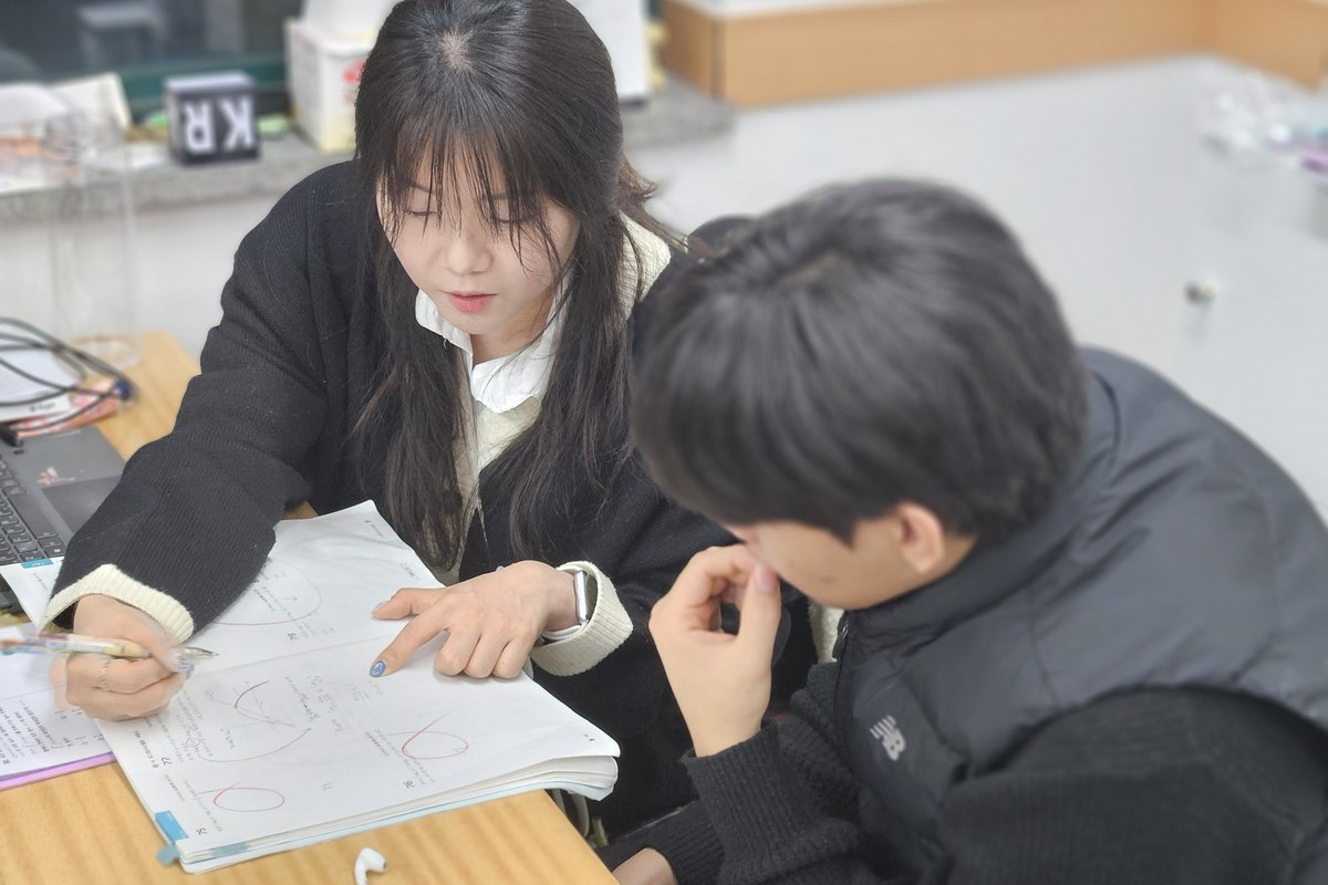 혜인쌤이 고등학생 옆에서 오답을 짚어가며 지도하는 모습